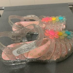 Clear with glitter closed toe sandles with three flowers on top. Size 5 kids.